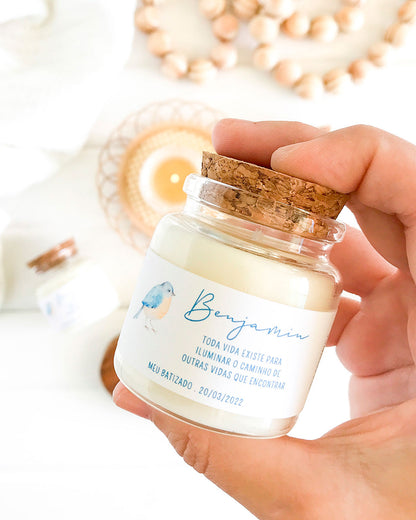 Mini vela feita em um vidro especial com tampa de rolha natural, adesivo com ilustração aquarelada e minimalista de um passarinho e mensagem personalizada para batizado. Com o nome da criança (Benjamim) e a mensagem: toda vida existe para iluminar o caminho de outras vidas que encontrar.