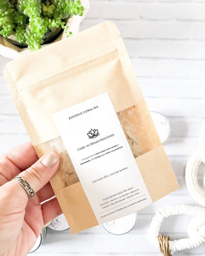 Envelope sachê kraft com visor transparente e etiqueta personalizada, fechamento tipo zip lock, com escalda-pés e sais de banho, para rituais de bem-estar e autocuidado. Com a frase: Cuide-se: Rituais Para Sentir / Uma porção de bem-estar, autocuidado e serenidade. Um tempo para viver a sua própria essência.