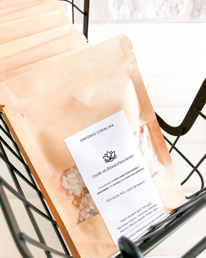 Envelope sachê kraft com visor transparente e etiqueta personalizada, fechamento tipo zip lock, com escalda-pés e sais de banho, para rituais de bem-estar e autocuidado. Com a frase: Cuide-se: Rituais Para Sentir / Uma porção de bem-estar, autocuidado e serenidade. Um tempo para viver a sua própria essência.